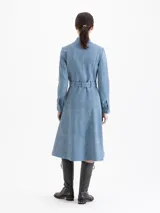 Tapado de cuero ovino color azul, con acabado símil denim. Tiene largo 7/8, cuello mao y cierre frontal con broches metálicos dorados y plateados. Incluye un lazo decorativo del mismo cuero en la cintura, mangas largas y vuelo hacia el ruedo. Cuenta con bolsillos ojal en los laterales.