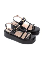 Sandalias negras de charol con plataforma de 5 cm, tiras frontales y pulsera ajustable al tobillo con detalle metálico dorado.