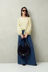 Bolso tipo hobo de cuero sintético negro con panel frontal de gamuza. Tiene correa de hombro ajustable y logo metálico plateado.