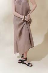Vestido largo color crudo con rayas verticales finas, breteles finos regulables, escote recto con bordado artesanal y tajos laterales.