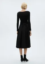 Vestido midi negro de punto con cuello redondo, mangas largas y falda acampanada. Incluye cinturón fino de cuero con hebilla metálica.