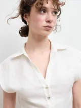 Camisa blanca de lino con cuello clásico, abotonada al frente y mangas cortas.