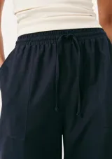 Pantalón de lino color crema, de corte recto y tiro alto, con cintura elástica ajustable con cordón y bolsillos laterales.