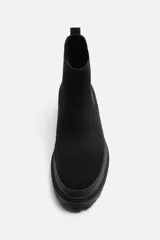 Bota Chelsea negra de cuero con acabado serraje, caña baja, puntera redondeada, tirador trasero y suela track con volumen.