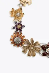 Collar dorado con dije de flores metálicas con brillos y joyas de diferentes colores.