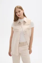 Chaleco color crema con detalles en tejido de espiga en la parte superior y bolsillos.