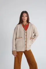 Cárdigan beige de punto con cuello en V, cierre frontal con botones, bolsillos de parche con ribete marrón y logo bordado en el pecho.