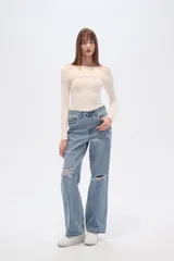 Pantalón jean azul claro, de corte recto y tiro alto, con roturas en las rodillas y detalles deshilachados en los bolsillos.