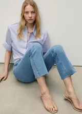 Pantalón de jean celeste de corte cropped y estilo flare, con tiro medio, cinco bolsillos, trabillas y bajo deshilachado.