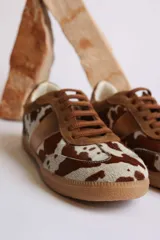 Zapatillas deportivas bajas con estampado animal print de vaca en blanco y marrón.