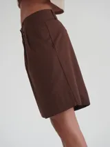 Bermuda negra de tiro medio, corte ancho, con bolsillos laterales y un ojal en la parte trasera.