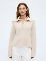 Sweater color beige de tejido de punto con cuello polo y cierre de medio cierre.