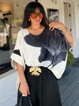 Blusa de satén color blanco con estampado de una flor negra y rayas verticales.