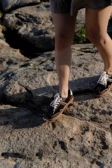 Zapatillas bajas de cuero color marrón oscuro con detalles en blanco y suela de goma color caramelo.