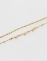 Set de dos pulseras doradas. Una es una cadena fina y la otra es una cadena con eslabones tubulares.