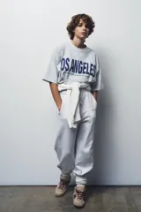 Camiseta gris jaspeado de corte amplio, cuello redondo y mangas cortas. Estampado frontal con la frase "Los Angeles 8500 Beverly Blvd, Los Angeles, CA 90048" en color azul.