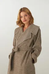 Tapado largo color beige con diseño de espiga, cuello solapa, cierre cruzado con cinturón y bolsillos laterales. Confeccionado en lana fina sin teñir.