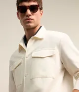 Campera trucker masculina de jeans color crudo, con cuello solapa, abotonado delantero, bolsillos con solapa y superficie lisa.