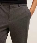 Pantalón de vestir gris con textura, corte slim, con trabillas en la cintura y cierre por botón y cremallera.