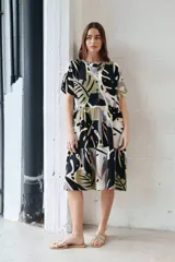 Vestido camisero midi con estampado de hojas en tonos negro, verde, gris y beige. Tiene cuello camisero, mangas cortas y cierre frontal con botones.