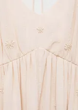 Vestido largo color rosa pálido con breteles finos y escote en V. Presenta pequeños bordados de flores.