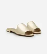 Sandalia plana de mujer color blanco hueso, con tira única ancha y puntera cuadrada abierta. Posee un taco bajo y suela de goma marrón.