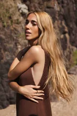 Vestido tejido color marrón, largo midi, con escote en V profundo y sisas profundas. Presenta un detalle de calado en la parte inferior a la altura de la rodilla.