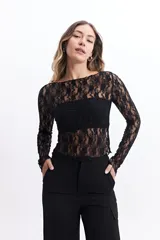 Remera negra de encaje liviano, de calce al cuerpo y manga larga. Tiene cuello redondo y terminación recta.