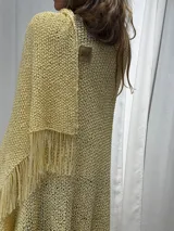 Ruana tejida a mano en color amarillo, de diseño liviano con flecos en el ruedo. Confeccionada en hilo, presenta un punto abierto y fluido.