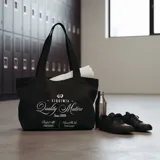 Bolso tote de tela rígida verde olivo con cierre, diseño serigrafiado, etiqueta y llavero oficial.