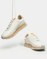 Sneaker de cuero liso color blanco con detalles en el talón y suela de corcho.