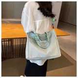 Bolso tipo tote color celeste con correa larga verde y asas cortas.