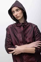 Capucha deportiva color borgoña, confeccionada en tafeta tornasolada con tiras ajustables que pueden anudarse formando un lazo.