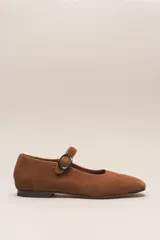 Zapato estilo Mary Jane color marrón, de cuero, con punta redondeada y tira sobre el empeine con hebilla.