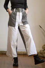 Pantalón de corte ancho con diseño de bloques de color blanco y estampado a cuadros en negro y blanco.