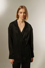 Blusa negra con corte cruzado, escote en V, mangas largas y lazo lateral para ajustar.
