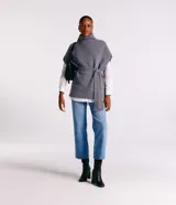 Poncho de punto color gris con cuello alto y diseño de manga corta sin sisa. Incluye un cinturón del mismo material para ajustar a la cintura y presenta una textura acanelada.