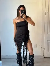 Vestido corto negro sin mangas, con escote recto y falda asimétrica con volados de encaje.