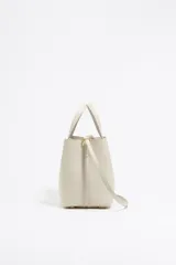 Bolso tote pequeño de piel reconstituida color gris claro, con estructura rígida, doble asa corta, correa extraíble, cierre con botón de presión, logo metálico BIMBA Y LOLA, acabados metálicos, bolsillo interior con cierre de cremallera e interior con logo grabado.
