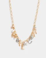 Collar dorado con cadena de eslabones y dijes colgantes plateados y dorados con forma de estrella, herradura, corazón, bota, cruz, llave y perla.