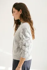 Sweater color arena de tejido de punto con cuello redondo y mangas largas con flecos.