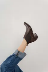 Botín negro de cuero con paneles laterales de gamuza y elástico en los tobillos. Tiene un pequeño taco cuadrado.