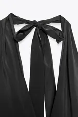 Vestido midi negro de tejido fluido, con cuello halter que se ata al cuello, escote en V y espalda descubierta.