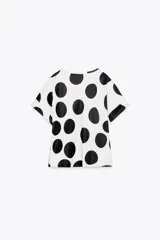 Top blanco con lunares negros grandes, cuello redondo y mangas cortas.
