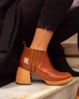 Bota corta de cuero color marrón con textura tipo reptil, paneles laterales de gamuza y elástico, tacón de madera y tirador trasero.