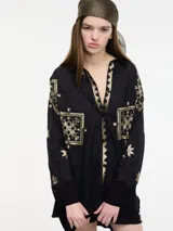 Camisa negra con bordados dorados, cuello camisero, botones frontales y bajo irregular.