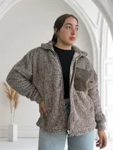 Campera de abrigo color marrón con textura de peluche, cierre frontal con cremallera y bolsillo de parche en el pecho.