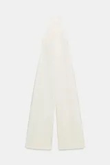 Mono largo color blanco, con cuello halter y espalda descubierta. Pierna ancha. Cierre en espalda con cremallera oculta en costura y botones.