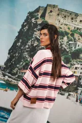 Remera de algodón y poliéster a rayas horizontales rojas y azul marino sobre fondo crudo. Tiene cuello tipo polo con botones, mangas amplias y corte oversized.