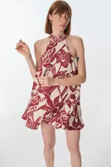 Vestido corto con estampado floral en tonos rojo y beige, cuello halter y corte evasé.